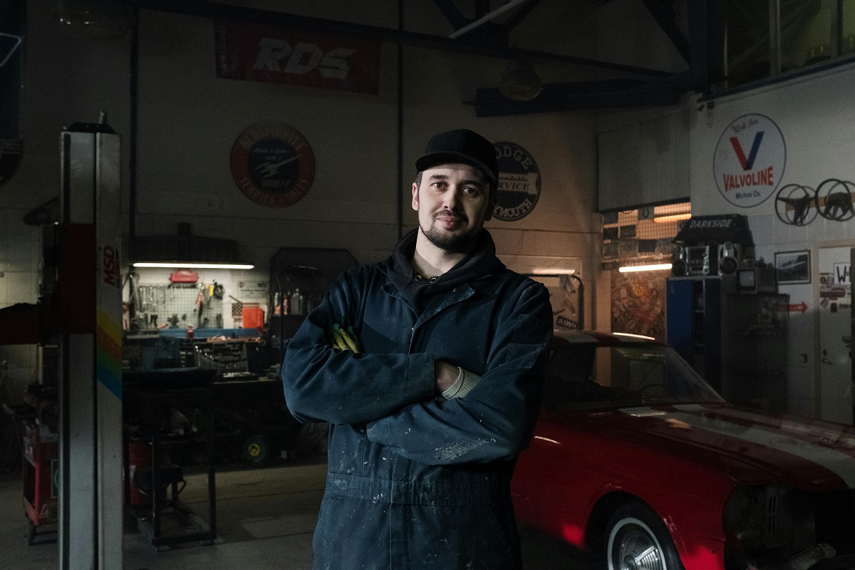 auto mechanic and a red car behind him